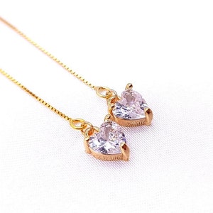 May include: A pair of gold dangle earrings with clear heart-shaped crystals.