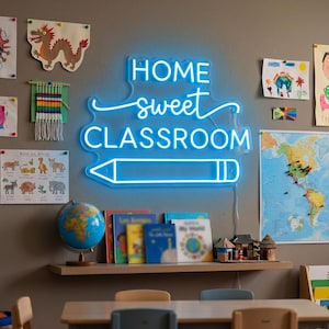 May include: A bright blue neon sign featuring the text HOME sweet CLASSROOM with a pencil graphic underneath. The sign is mounted on a wall surrounded by various children's drawings, a world map, and a shelf holding books and a globe.