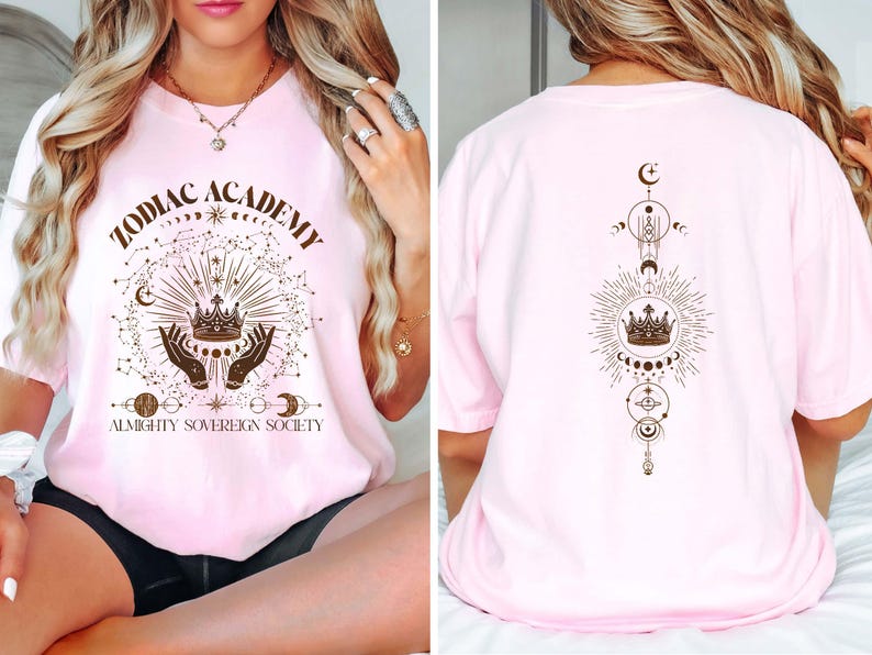 Pu&ograve; includere: Maglietta rosa con un design grafico di una corona, stelle e il testo "Zodiac Academy Almighty Sovereign Society". Il retro della maglietta ha un design simile con una corona e simboli celesti.