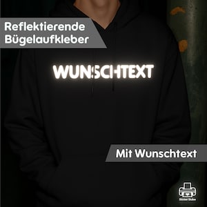 Könnte beinhalten: Schwarzer Kapuzenpullover mit dem Wort "WUNSCHTEXT" in reflektierenden weißen Buchstaben auf der Brust. Der Hoodie hat auch den Text "Mit Wunschtext" und "Reflektierende Bügellaufkleber" im Bild.
