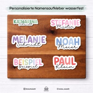 Könnte beinhalten: Ein Holzbrett zeigt sechs personalisierte, wasserfeste Namensaufkleber. Die Aufkleber zeigen Namen wie Katharina, Melanie, Noah und Paul in verschiedenen bunten Schriftarten. Der Text "Personalisierte Namensaufkleber wasserfest" steht oben.