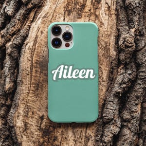Op de afbeelding: Een mintgroene smartphonehoes met een drievoudige camera-opstelling in de linkerbovenhoek en de naam Aileen in een wit cursief lettertype gedrukt in het midden van het gladde, effen gekleurde beschermende oppervlak.