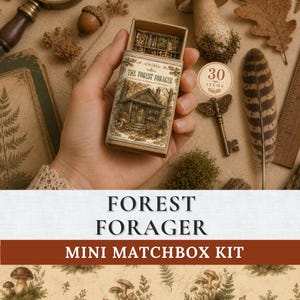 May include: A small rectangular matchbox kit labeled The Forest Forager, featuring an illustration of a woodland cabin on the front. The box is partially open, revealing small compartments containing various tiny natural items and treasures.