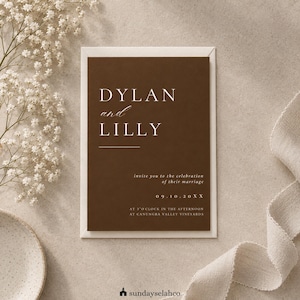 May include: A rectangular wedding invitation card with a dark brown background and white text. The card reads DYLAN and LILLY, invite you to the celebration of their marriage, 09.10.20XX, at 3 o'clock in the afternoon at Canungra Valley Vineyards.