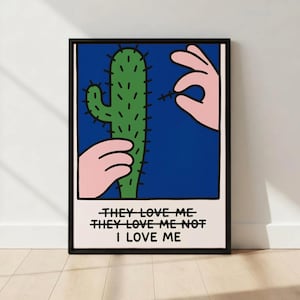 May include: A framed art print with a green cactus on a blue backdrop, pink hands, and the text "THEY LOVE ME, THEY LOVE ME NOT, I LOVE ME". The black framed artwork has a minimalist pop art style, suitable for home decor.