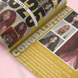 May include: A yellow and black graduation yearbook with the text "Class of 2023" and "Congratulations" on the cover. The yearbook features photos of several young women.
