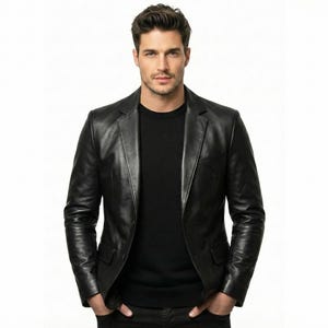 Puede incluir: Un blazer de cuero negro con solapa clásica con muescas. La chaqueta tiene cierre de dos botones y un corte entallado. La persona de la imagen lleva debajo una camiseta negra de cuello redondo. El fondo es blanco liso.