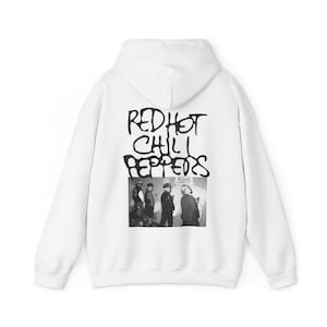 May include: White hooded sweatshirt with a black graphic print of the band Red Hot Chili Peppers. The graphic includes the band's name in graffiti-style lettering and a black and white photo of the band members.