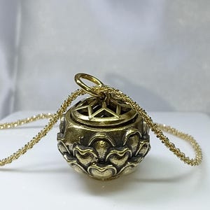 Op de afbeelding: Een gouden ketting met een hanger in de vorm van een lotusbloem. De hanger heeft een stervormige opening aan de bovenkant en is bevestigd aan een delicate gouden ketting.