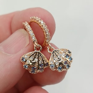 Pendientes de aro pequeños con conchas marinas y circonitas azules.