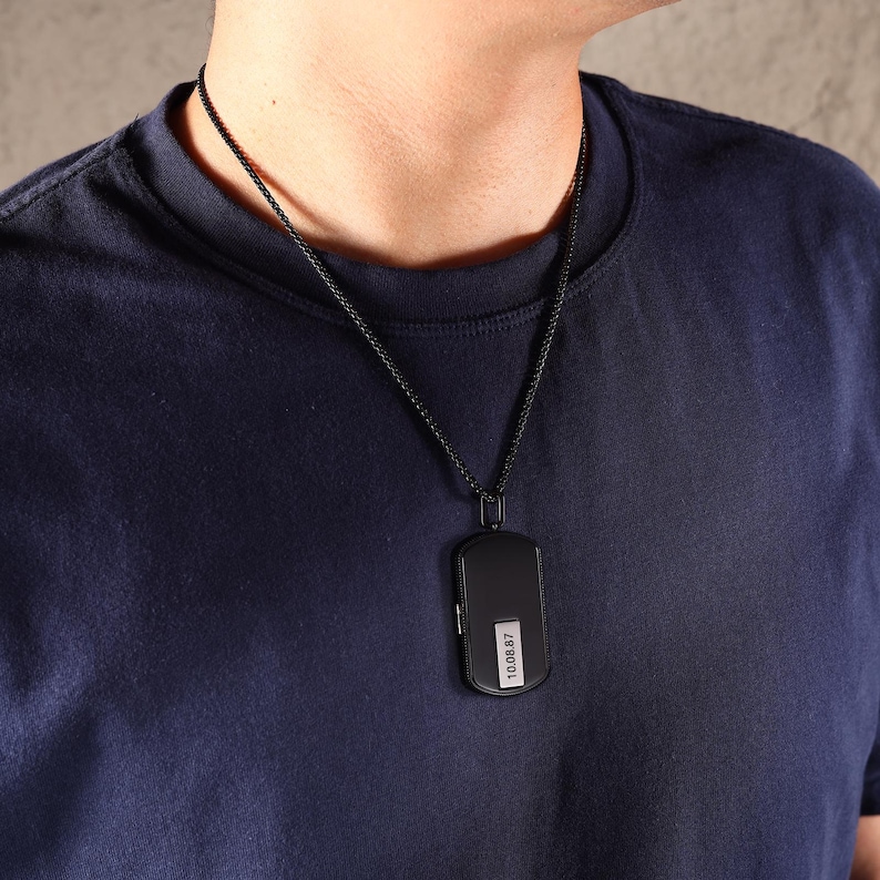 May include: A black pendant necklace with a rectangular pendant. The pendant has a small white label with the numbers "10.08.87" printed on it. The necklace chain is also black.