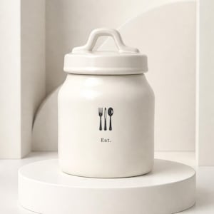 Rae Dunn Charming white ceramic canister with 'EAT' in bold black lettering.