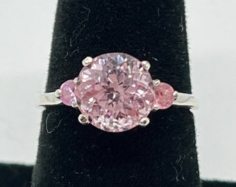 May include: A silver ring featuring a large pink gemstone surrounded by three smaller pink gemstones.