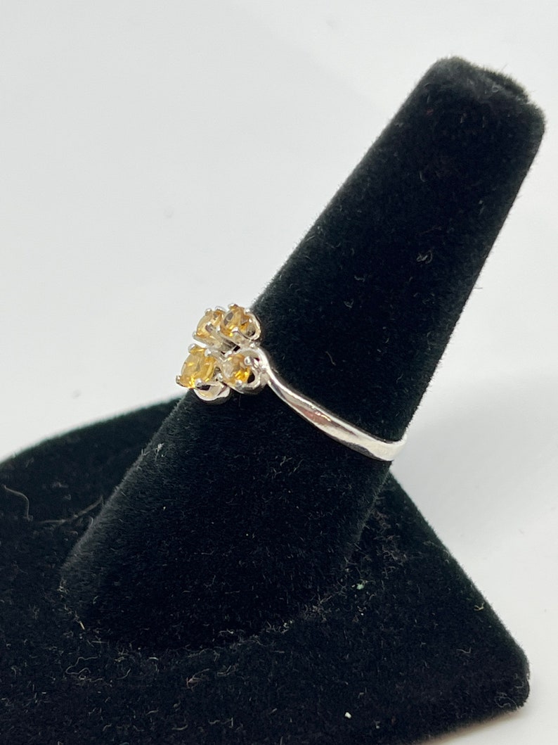 May include: A silver ring with a cluster of yellow gemstones set in a flower shape.