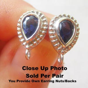Peut inclure: Gros plan d'une paire de boucles d'oreilles en argent avec des pierres précieuses bleu foncé en forme de goutte. Les boucles d'oreilles ont un bord perlé et une boucle. Le texte "Close Up Photo" est visible.