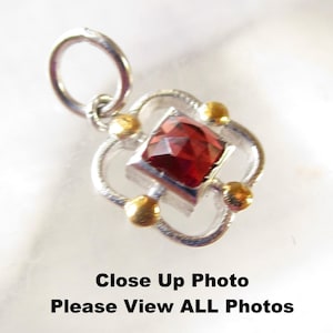 May include: A silver pendant with a square, faceted, deep red gemstone at the center. The pendant has a four-petal design with gold-colored accents. The text at the bottom reads "Close Up Photo Please View ALL Photos."