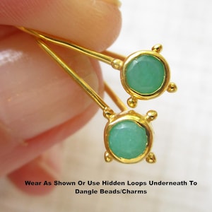 May include: A pair of gold-toned earrings featuring round, faceted mint green stones set in metal bezels with four small prongs. The text "Wear As Shown Or Use Hidden Loops Underneath To Dangle Beads/Charms" is printed at the bottom of the image.