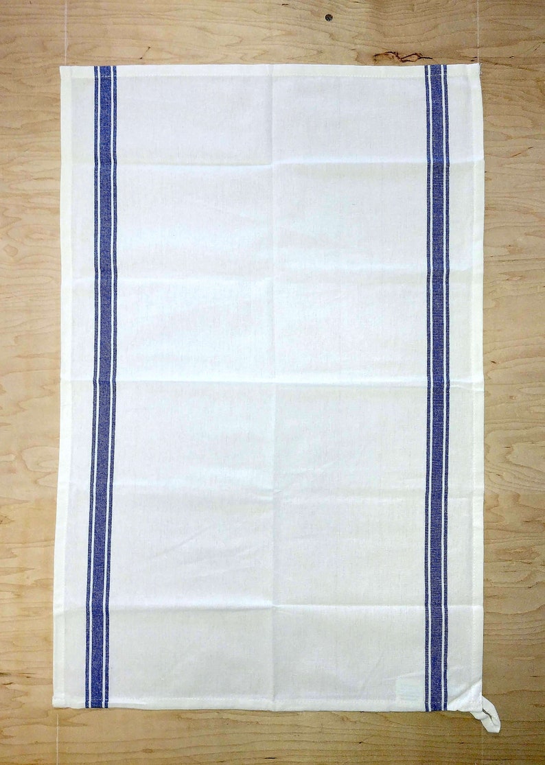 May include: White kitchen towel with two blue stripes along the sides.