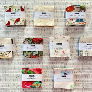 May include: An overhead shot of ten fabric bundles with various holiday-themed patterns. The bundles are labeled with phrases like "Winter Friends," "Purrfect Christmas," and "Berry & Pine." The background is a sheet of music.
