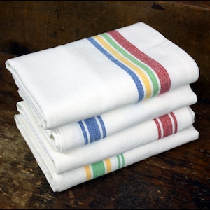 May include: A stack of four white kitchen towels with colored stripes. The top towel has red, yellow, and green stripes. The second towel has blue stripes. The third towel has red stripes. The bottom towel has green and yellow stripes.