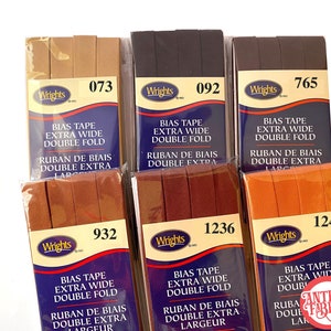 May include: Six packages of Wrights bias tape in various colors, including brown, black, orange, and red. Each package is labeled with the Wrights brand name and the color number. The tape is extra wide and double fold. The packages are arranged in two rows of three.