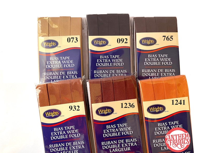 May include: Six packages of Wrights bias tape in various colors, including brown, black, orange, and red. Each package is labeled with the Wrights brand name and the color number. The tape is extra wide and double fold. The packages are arranged in two rows of three.