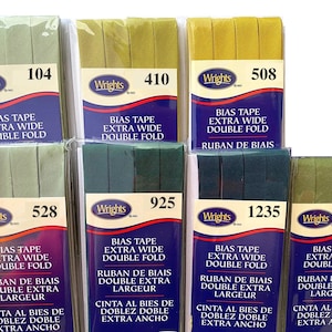 May include: Eight packages of Wrights bias tape in various shades of green. Each package has a label with the Wrights logo and the product name "Bias Tape Extra Wide Double Fold". The labels also include the product number, such as "104", "410", "508", "528", "925", "1235", and "1239".