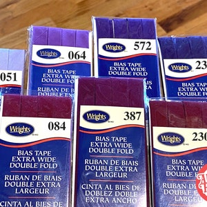 May include: Assortment of six packages of Wrights bias tape in various colors, including purple, burgundy, and navy blue. Each package features the brand name Wrights and a product description, including "Bias Tape Extra Wide Double Fold" and the corresponding product number.