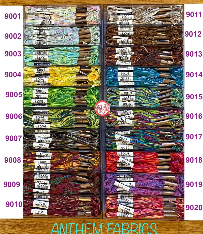 May include: A close-up image of a collection of embroidery floss spools organized in a drawer. The spools are arranged in rows and columns, with each row labeled with a number from 9001 to 9020. The spools are a variety of colors, including blue, green, yellow, orange, red, purple, and brown.