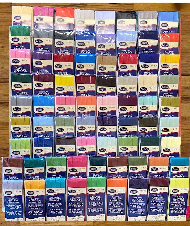 May include: A collection of 48 spools of bias tape in various colors and widths. The spools are labeled with the brand name "Wrights" and the product number. The bias tape is a double-fold, extra wide bias tape.