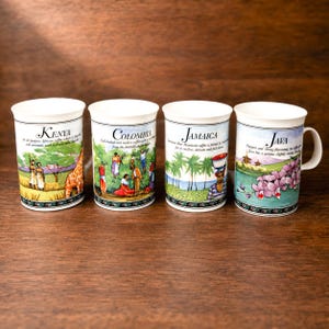 Może przedstawiać: Cztery białe ceramiczne kubki z kolorowymi ilustracjami i napisami przedstawiającymi regiony kawowe: Kenia z żyrafą, Kolumbia ze zbieraczami kawy, Jamajka z palmami i Jawa z orchideami. Każdy kubek posiada ozdobną bordiurę u podstawy.