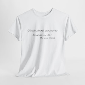 May include: Plain white t-shirt featuring the quote "Be the change you wish to see in the world." by Mahatma Gandhi. The text is in a cursive font. A minimalist design, suitable for everyday wear.