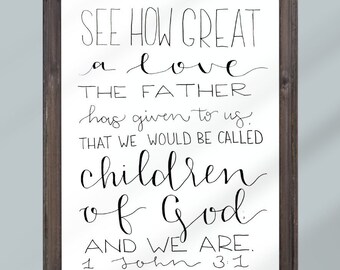 Puede incluir: Texto escrito a mano en blanco y negro sobre un fondo blanco en un marco de madera marrón. El texto dice "See how great a love the Father has given to us. That we would be called children of God. And we are. 1 John 3:1"