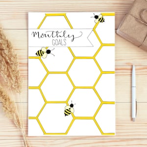 May include: A white printable planner with a honeycomb pattern and yellow bees. The text "Monthly Goals" is at the top of the page.