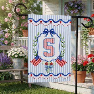 May include: A garden flag with a blue and white striped design. The flag displays the number '5' in red and white, framed by a wreath, bows, and American flags. Red and blue details complete the design, suitable for outdoor use.