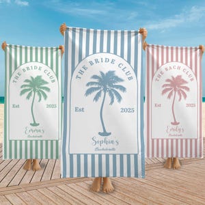 May include: Three striped beach towels in green, blue, and pink, each with a palm tree design and the text "THE BRIDE CLUB" or "THE BACH CLUB". The towels are personalized with names and the year 2025.