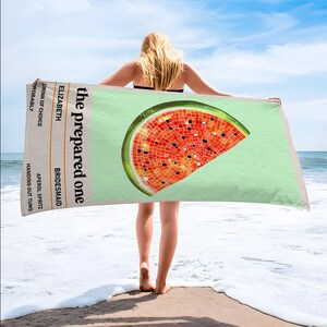 May include: A beach towel with a watermelon slice design. The towel has a light green background and a mosaic-style watermelon slice in red, orange, and black. Text on the towel reads "the prepared one" and "Elizabeth, Bridesmaid".