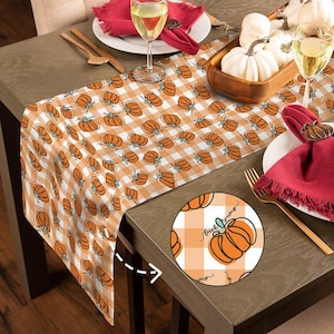 May include: A fall-themed table runner with a repeating pattern of orange pumpkins on a white and orange checkered background. The runner is displayed on a wooden table, with place settings and decorative pumpkins.