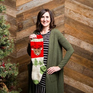 May include: A handmade Christmas stocking with a red top, featuring the name "JASON" in green letters. The stocking has a reindeer design and green trees on a cream-coloured background. The heel and toe are green.