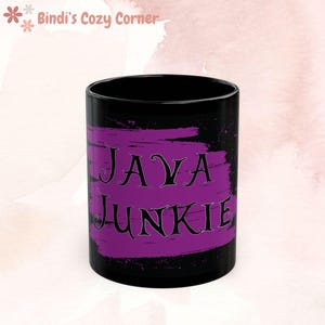 May include: Black ceramic mug with a purple paint splatter design and the text "JAVA JUNKIE" in black.