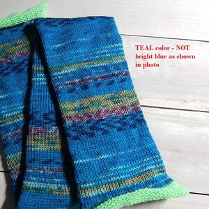 May include: A hand-knitted scarf in shades of teal, blue, and accents of yellow, red, and green. The scarf has a vibrant teal body with a contrasting light green knitted border. The text in the image says "TEAL color - NOT bright blue as shown in photo."