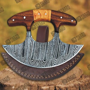 May include: A curved, Damascus steel cleaver with a wooden handle. The cleaver has a brown leather sheath with stitching.