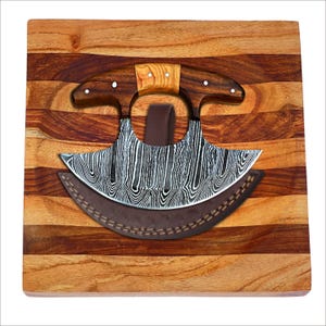 May include: A curved, stainless steel cleaver with a wooden handle and a leather sheath, resting on a wooden cutting board with a striped pattern.