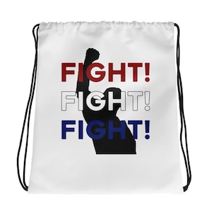 May include: White drawstring bag featuring a silhouette of a person raising their fist in the air. The words "FIGHT!" are repeated three times in red, white, and blue.