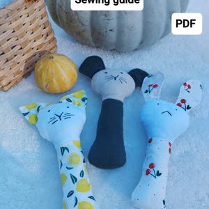 May include: Three DIY sewing patterns for baby toys: a cat, a mouse, and a bunny. Each pattern features a different fabric design. The patterns are available as a PDF download. The text "Sewing guide" and "PDF" are visible in the image.