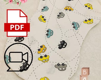 Könnte beinhalten: Weißes Baby-Lätzchen mit einem Muster aus bunten Cartoon-Autos in Gelb, Grau, Schwarz und Blau. Das Lätzchen hat ein genähtes Design und das Wort "BABY" in Holzblöcken. Ein PDF-Symbol und ein Videosymbol sind ebenfalls vorhanden.