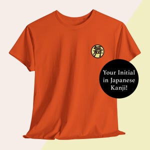 May include: Orange t-shirt with a yellow circle containing a black kanji character. The text "Your Initial in Japanese Kanji!" is written in black on a white circle.