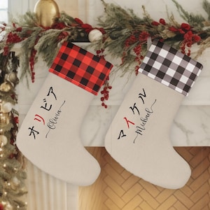 May include: Two Christmas stockings with Japanese text and English names, "Olivia" and "Michael". The stockings are beige with red and black buffalo plaid and black and white buffalo plaid cuffs.