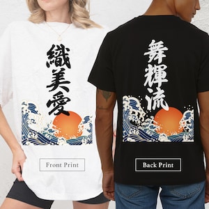 Comparison of t-shirt print placements on two models. On the left, a woman wears a textured white t-shirt featuring the Japanese wave and sun graphic with black Kanji characters on the front, labeled "Front Print". On the right, a man wears a black t-shirt featuring the same graphic with white Kanji characters on the back, labeled "Back Print".