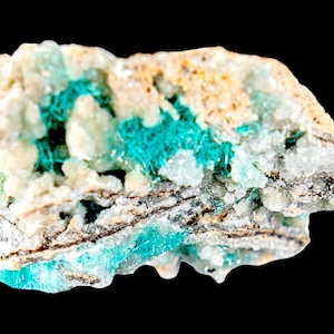 Op de afbeelding: Een close-up van een mineraalmonster met een ruwe, onregelmatige vorm. Het mineraal heeft een mix van kleuren, waaronder wit, bruin en levendig turquoise. Het turquoise verschijnt in clusters en aderen door de steen, wat een opvallend contrast creëert.